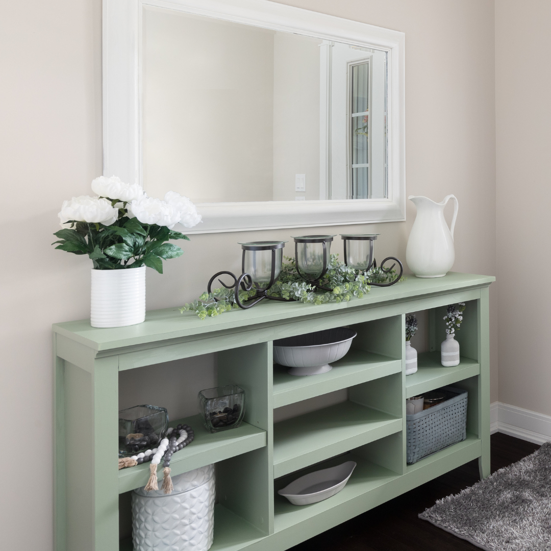 Light green console table with decorative items against a beige wall.