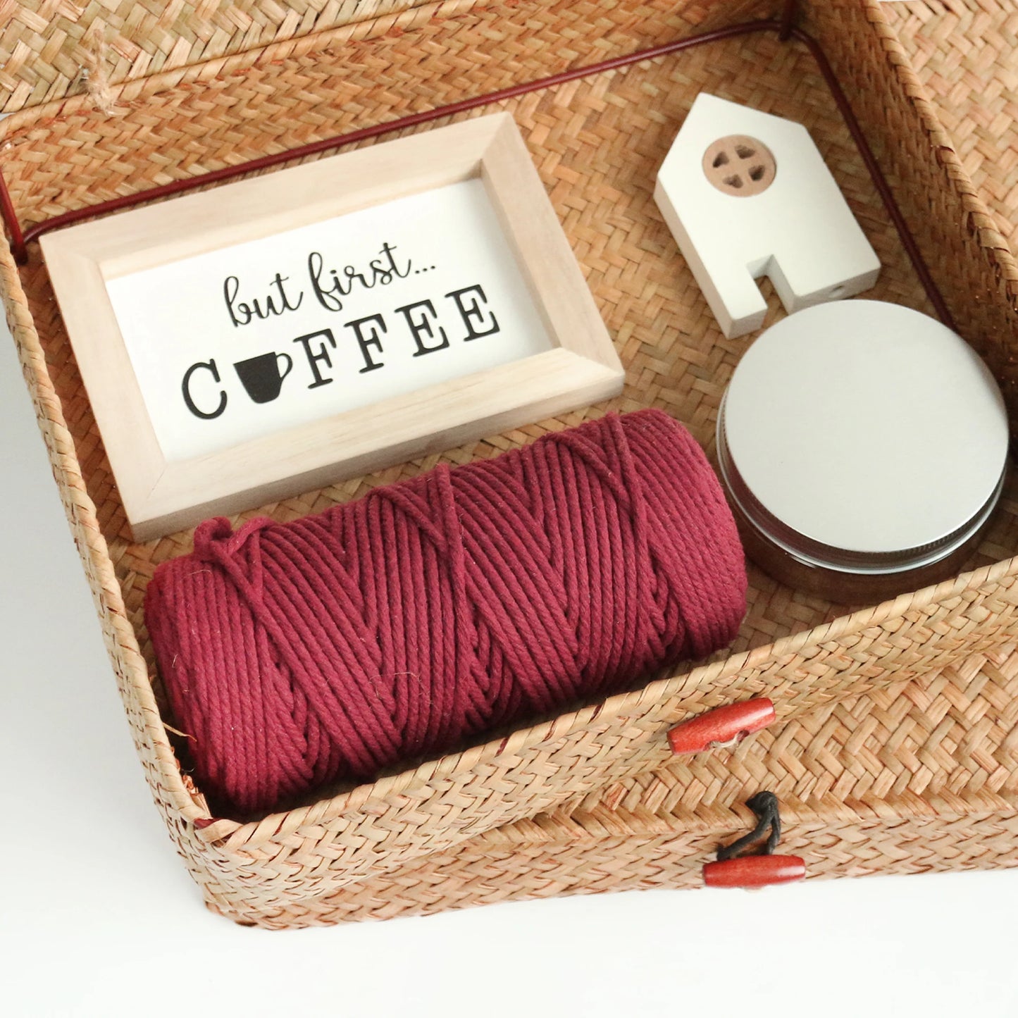 Woven basket with yarn, small sign, and decorative items on a white background
