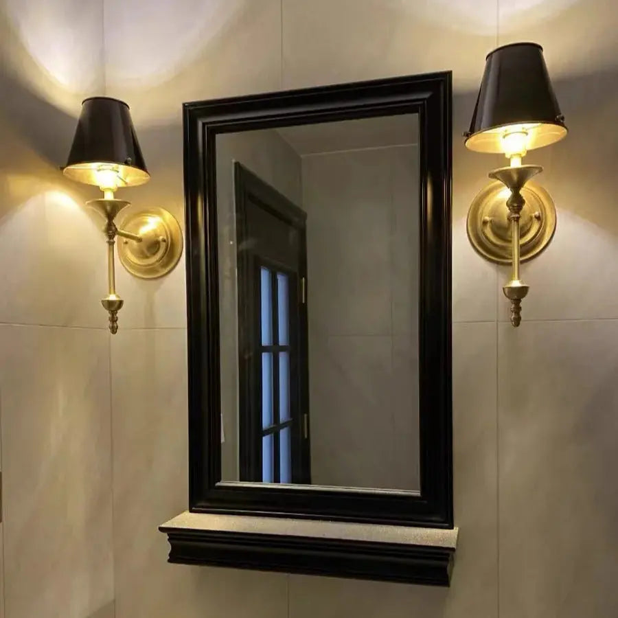 Bathroom vanity with black-framed mirror and wall sconces