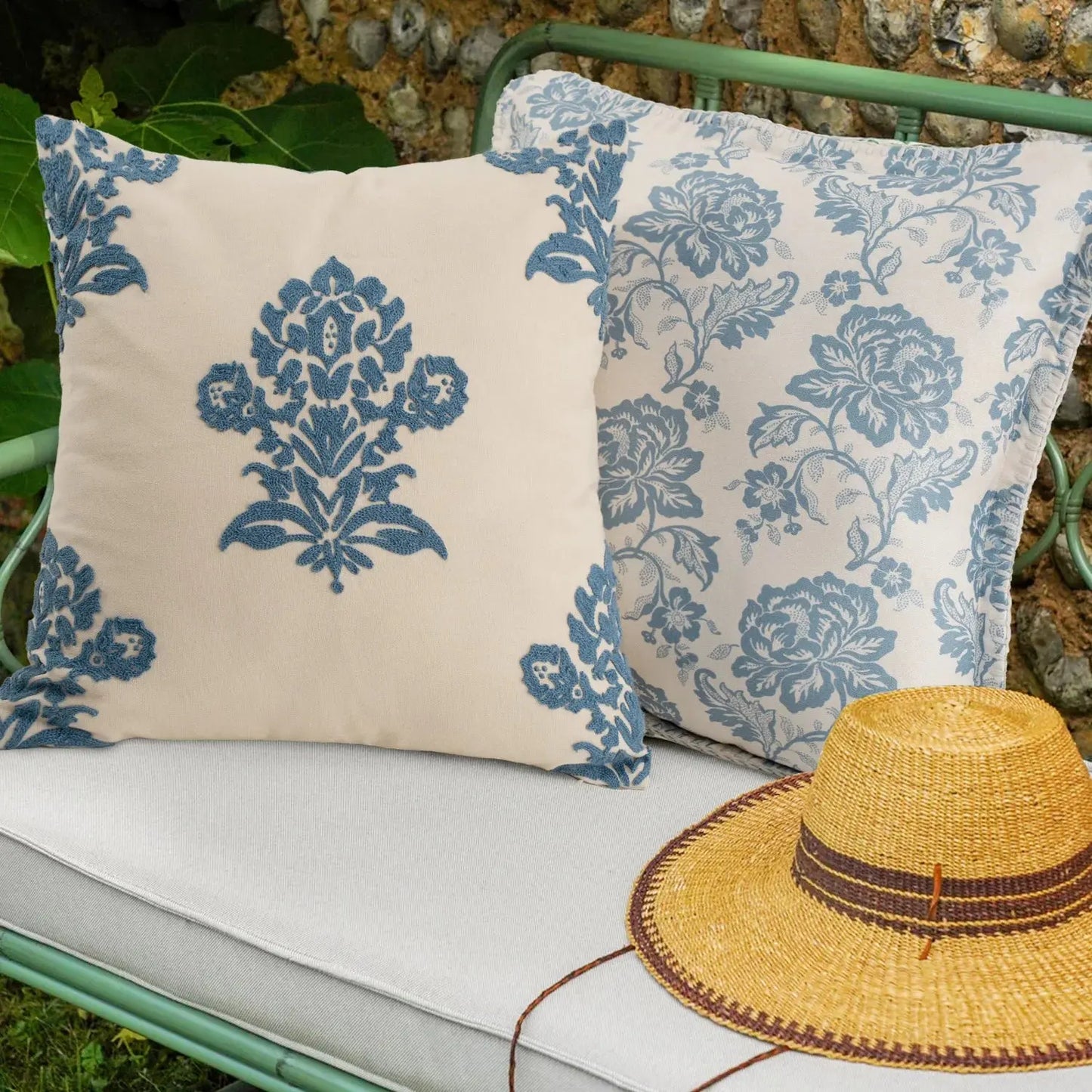 Two decorative pillows with blue patterns on a bench next