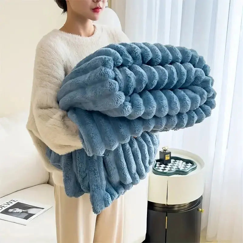 Person holding a large blue textured blanket in a room