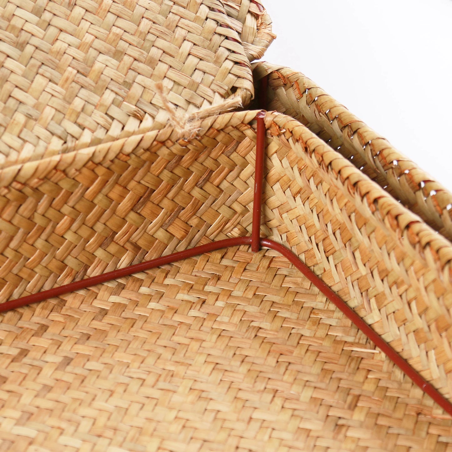 Close-up of a woven straw hat with a red band on a white background