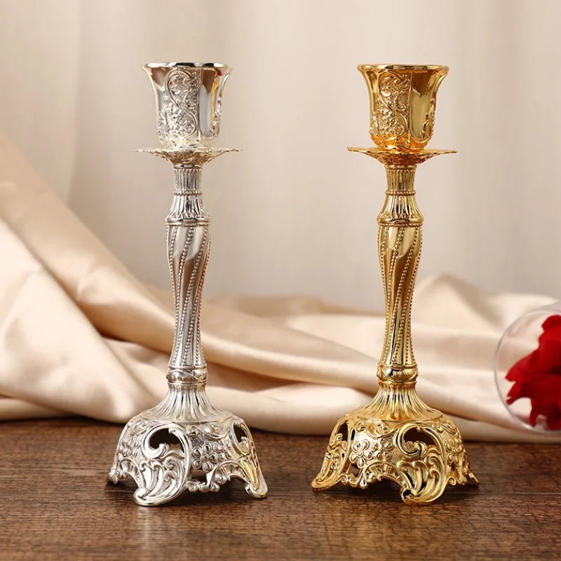 Silver and gold candle holders on a wooden surface with a beige fabric background