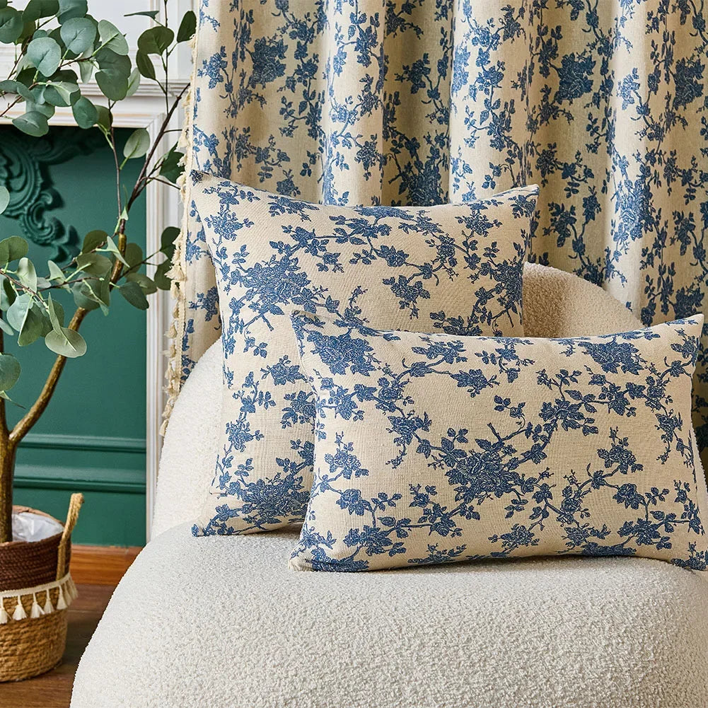 Floral-patterned cushions on a sofa with decorative plant and green wall in the background