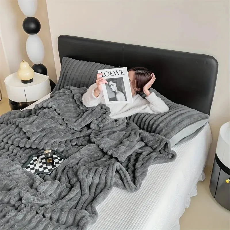 Person lying on a bed with a gray textured blanke