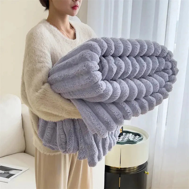 Person holding a large gray textured blanket in a room