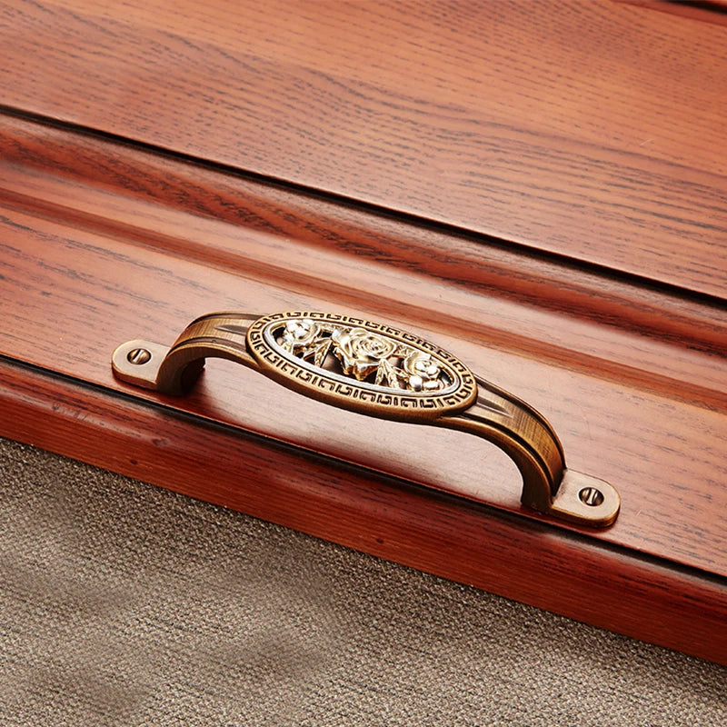 Wooden box with a decorative brass handle on a textured surface