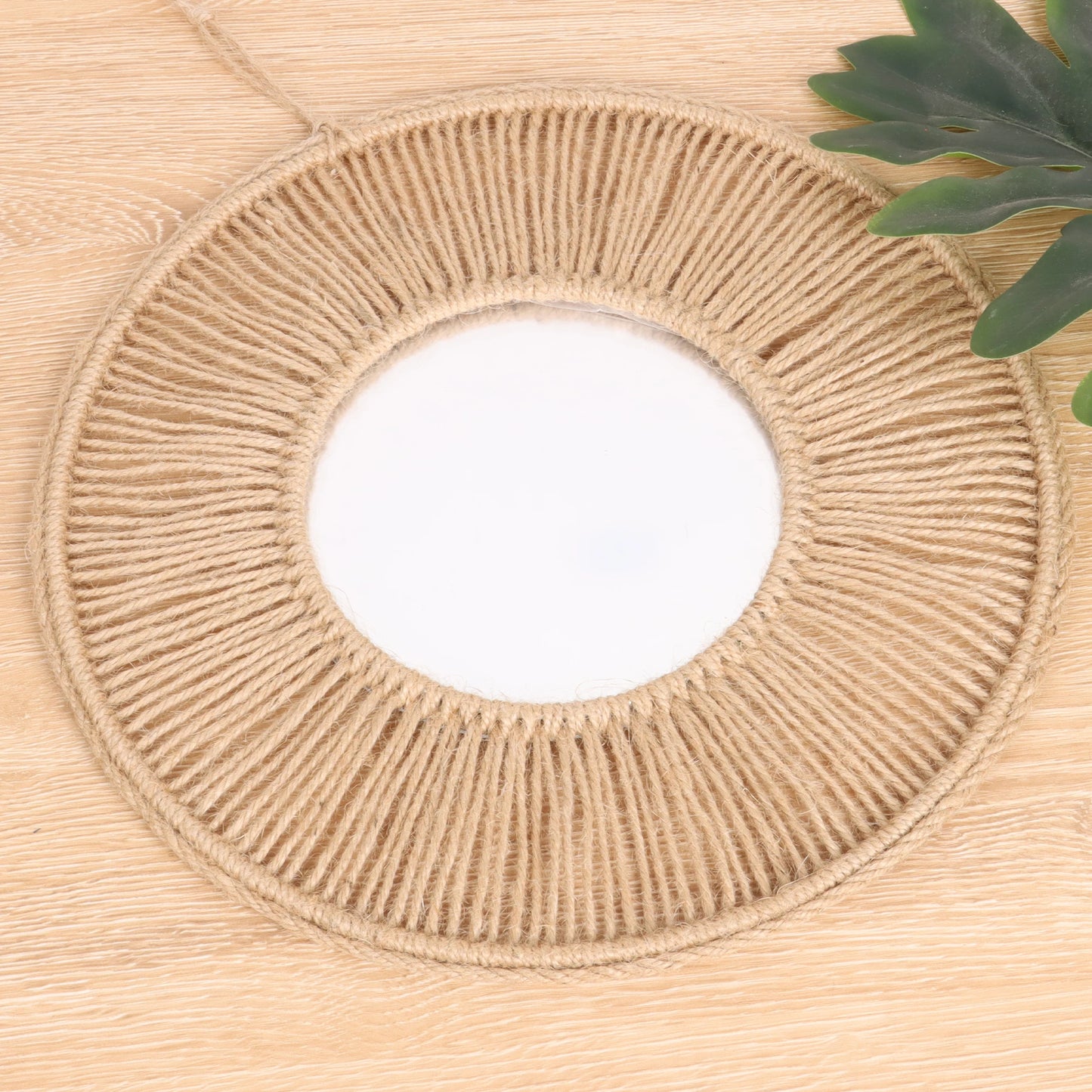 Round woven mat on a wooden floor with a plant in the corner