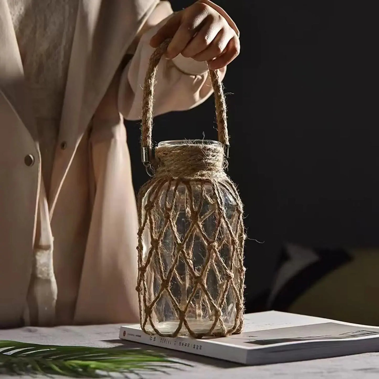 Hand holding a glass jar with a rope handle