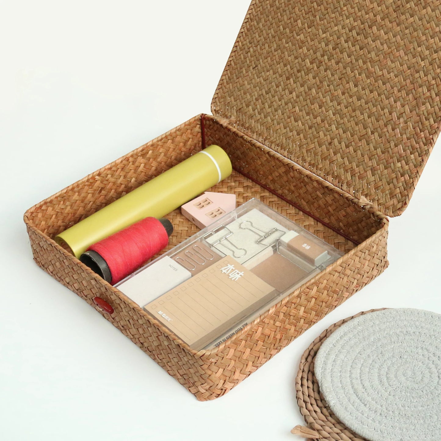 Woven basket with stationery items including pens and a box on a white background