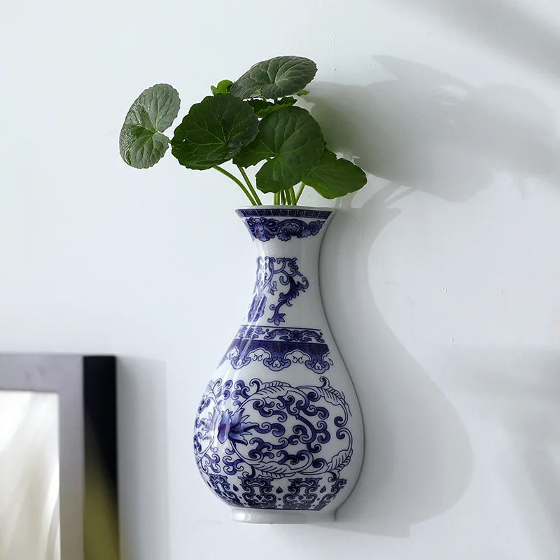 Blue and white decorative vase with green plant on a white background