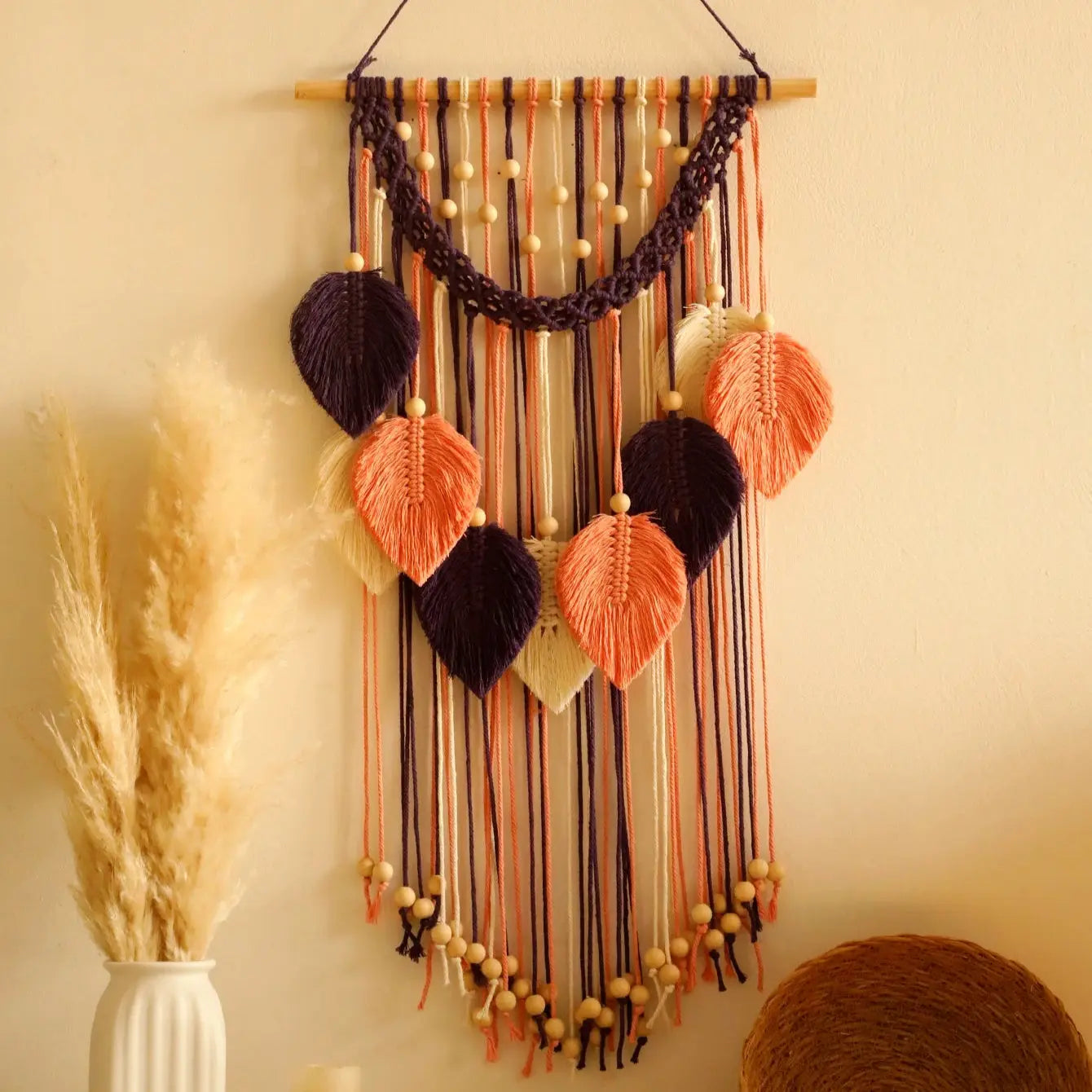 Decorative wall hanging with ribbons and beads on a wall.