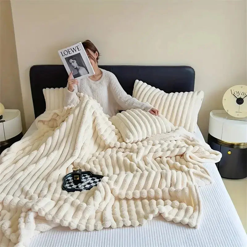 Person holding a book under a white blanket on a bed