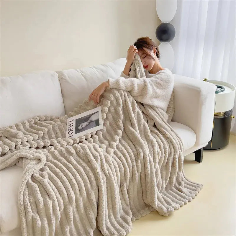 Woman sitting on a couch wrapped in a textured beige blanket