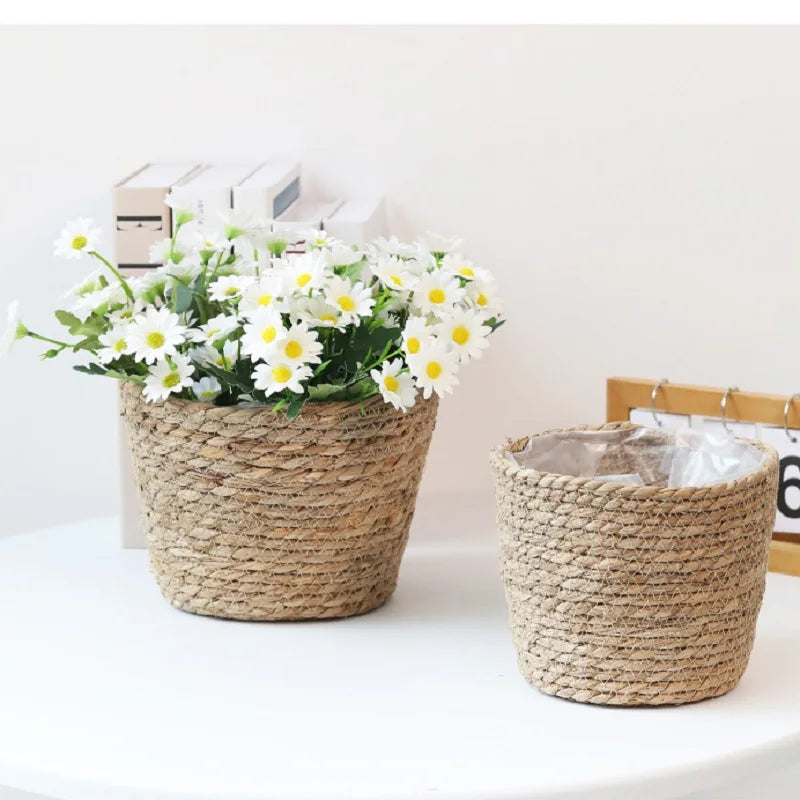 Two woven baskets with one containing white flowers on a light surface.