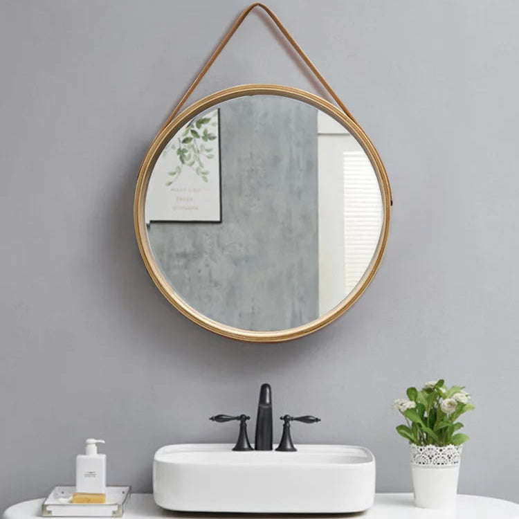 Round mirror with wooden frame hanging above a sink in a bathroom setting.