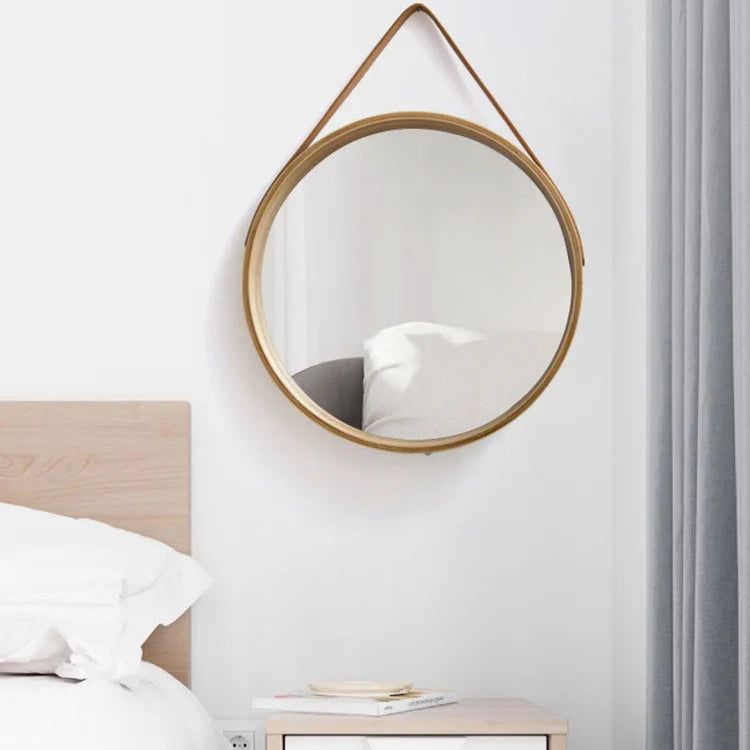 Round mirror with wooden frame on a wall in a bedroom setting