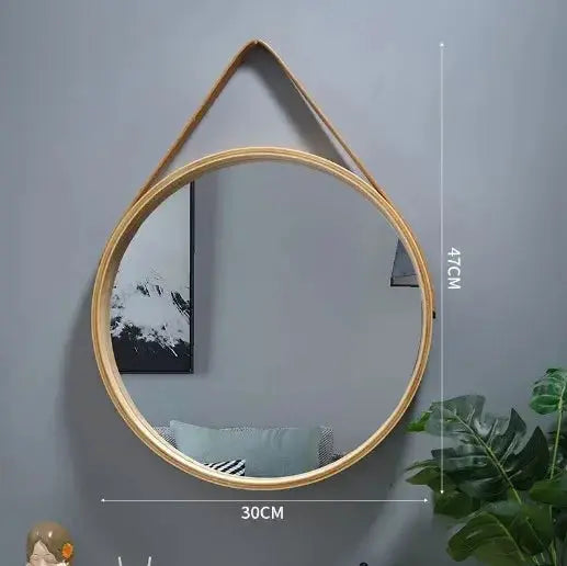 Round wooden-framed mirror on a grey wall
