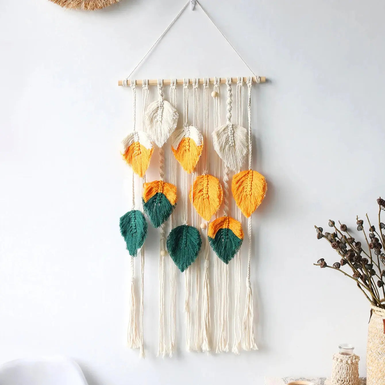 Decorative wall hanging with colorful leaves on a white wall