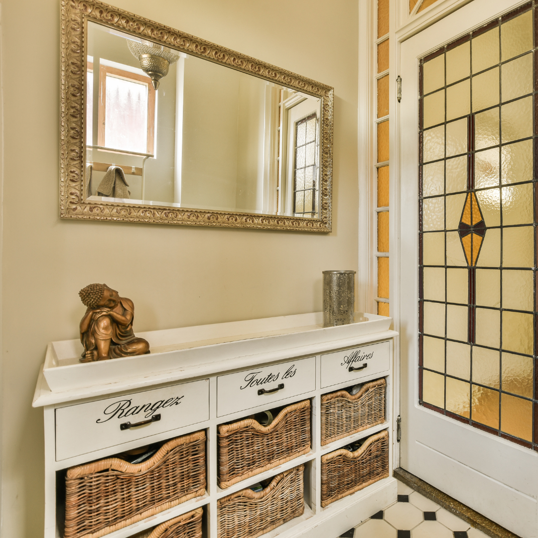 Decorative interior with a mirror, cabinet with wicker baskets, and stained glass door.