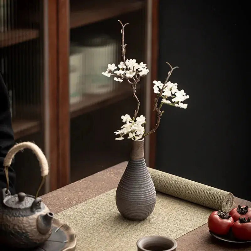 Gray textured vase with white flowers on a wooden table