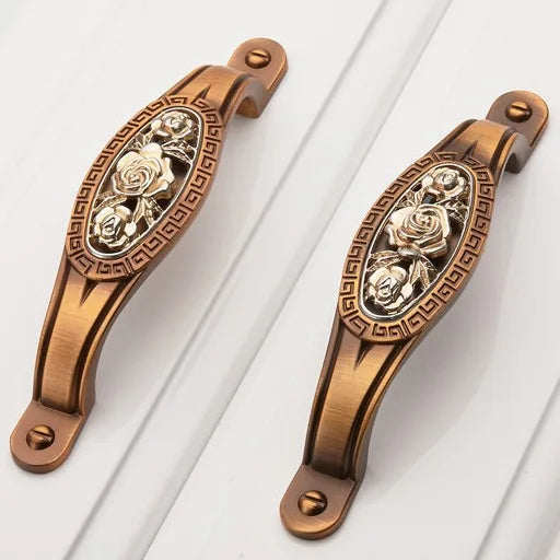 Decorative bronze handles with floral designs on a white background