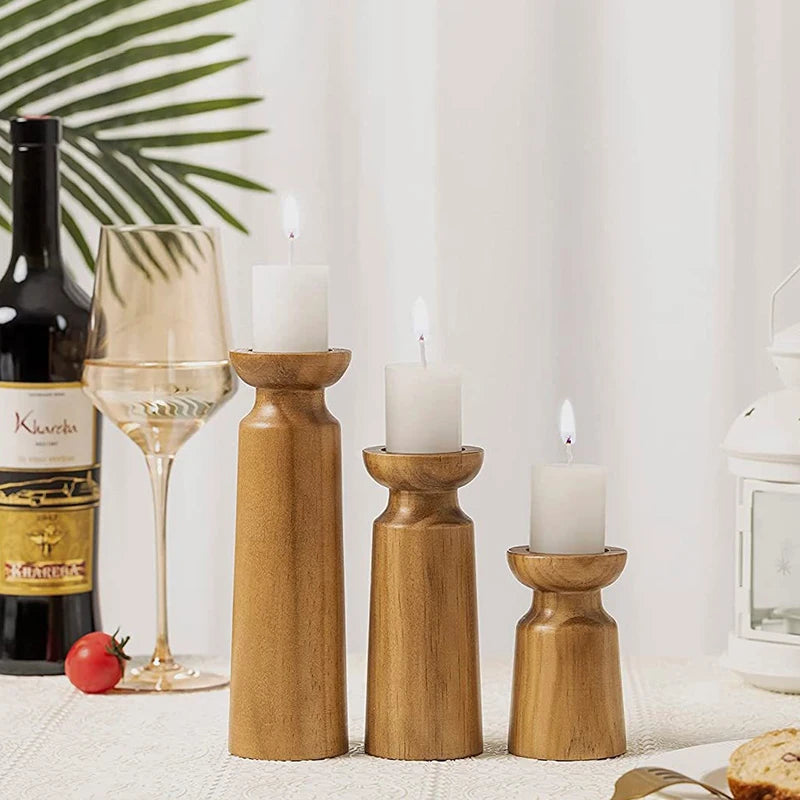 Wooden candle holders with candles on a table with a bottle of wine and glass.