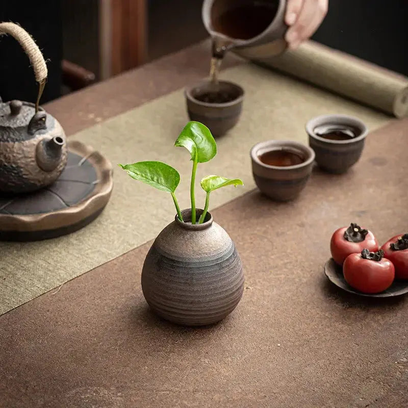 Ceramic vase with a plant on a wooden table