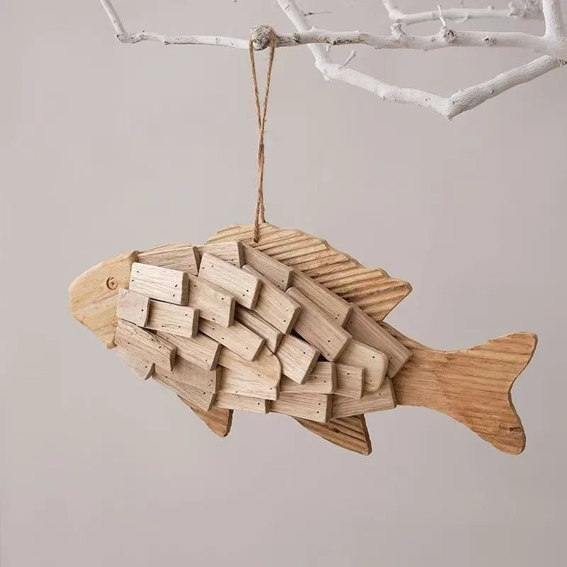 Wooden fish-shaped ornament hanging on a branch against a neutral background