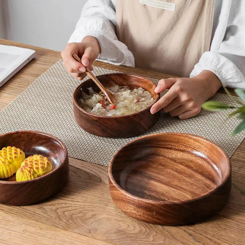 Person eating from a wooden bowl on a table