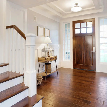 Foyer with wooden staircase, door, and side table with lamp.