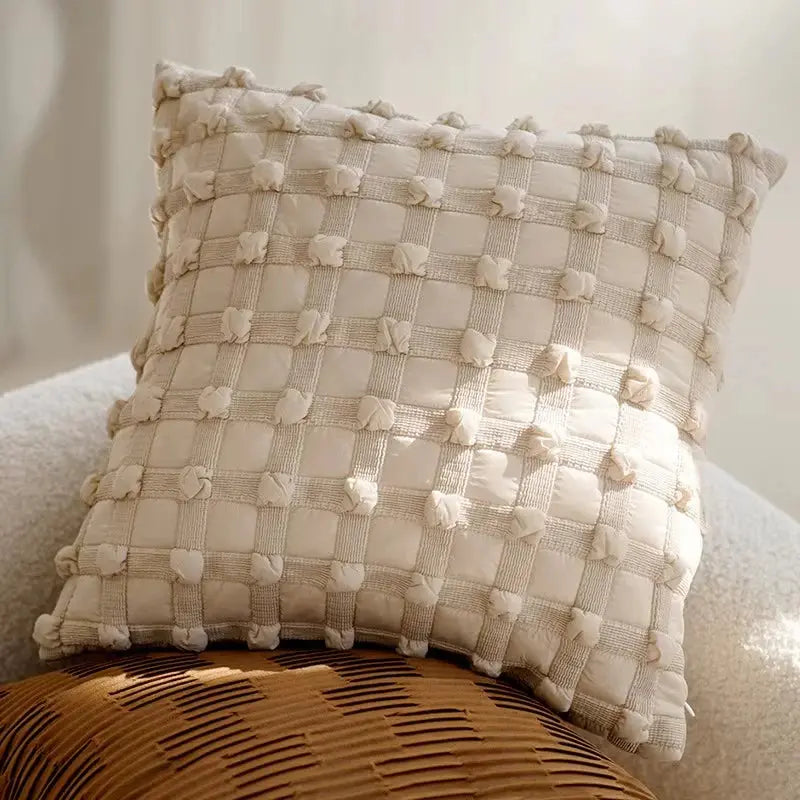 Textured beige pillow on a chair with a neutral background