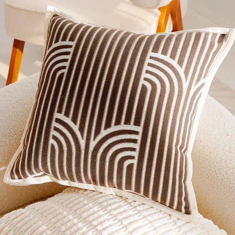 Decorative pillow with brown and white geometric pattern on a beige sofa.