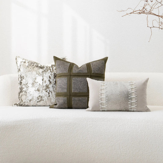 Three decorative pillows on a white sofa with a neutral background