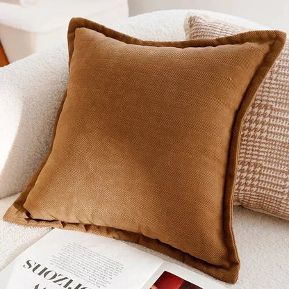 Brown pillow on a sofa with a magazine underneath