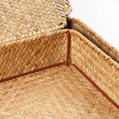 Close-up of a woven straw hat with a red band on a white background