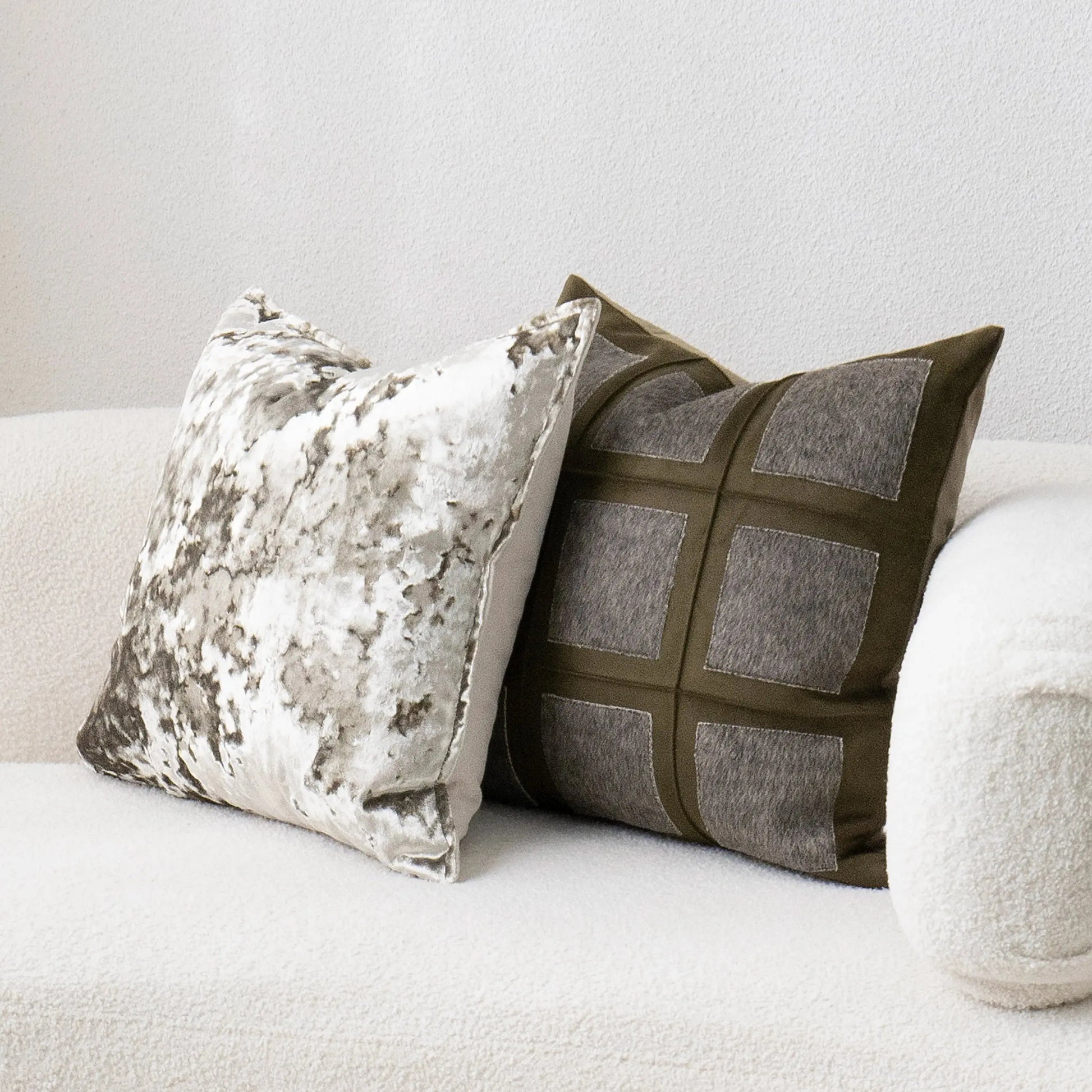 Two decorative pillows on a white sofa against a light gray wall.