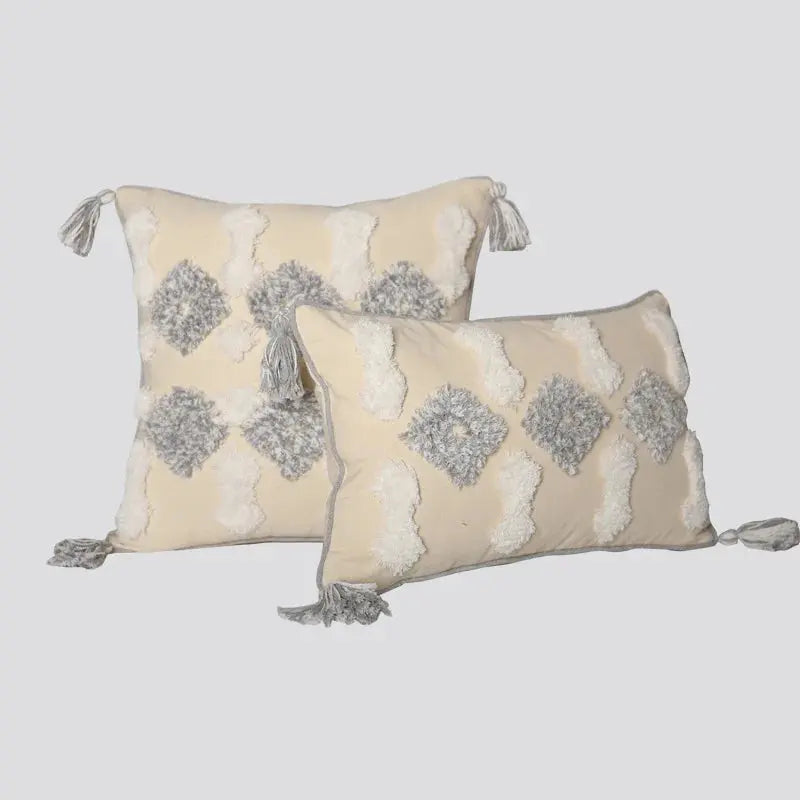 Two decorative pillows with geometric patterns and tassels on a light gray background