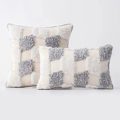 Two decorative pillows with a checkered pattern of gray and white on a light background