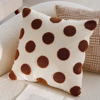 White pillow with brown polka dots on a beige couch