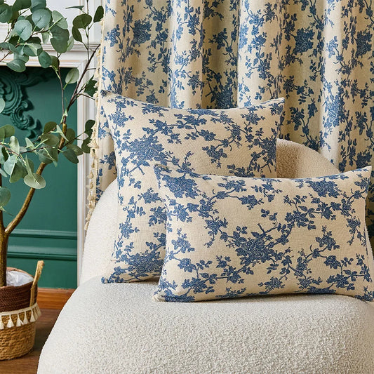 Floral-patterned cushions on a sofa with decorative plant and green wall in the background