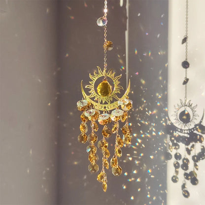Decorative sun and moon hanging ornament with crystals on a reflective surface.