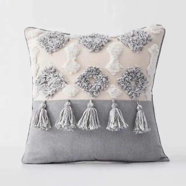 Decorative pillow with tassels and embroidered patterns on a plain background