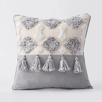 Decorative pillow with tassels and embroidered patterns on a plain background