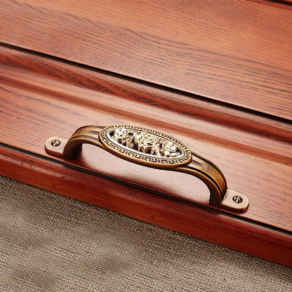 Wooden box with a decorative brass handle on a textured surface