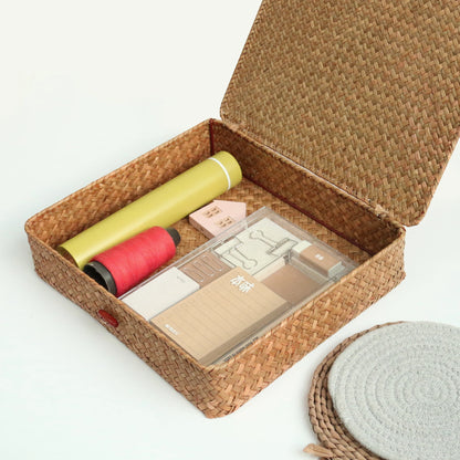 Woven basket with stationery items including pens and a box on a white background