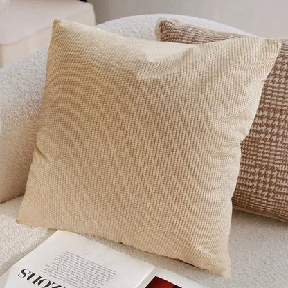 Beige textured pillow on a sofa with a magazine underneath