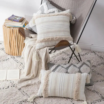 Decorative pillows with tassels on a textured rug in a cozy room setting.