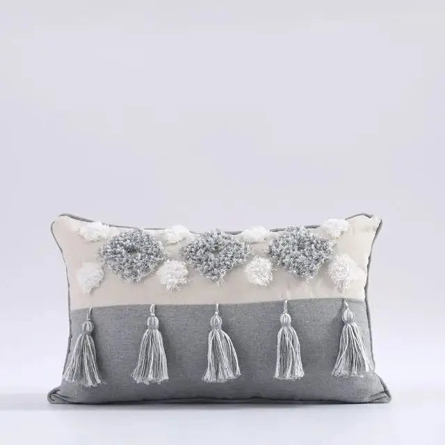 Decorative pillow with tassels and pom-poms on a light gray background