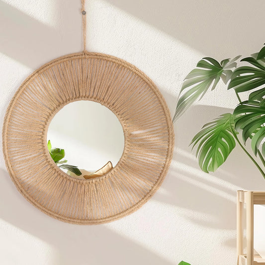 Round woven mirror hanging on a wall with green leaves in the background